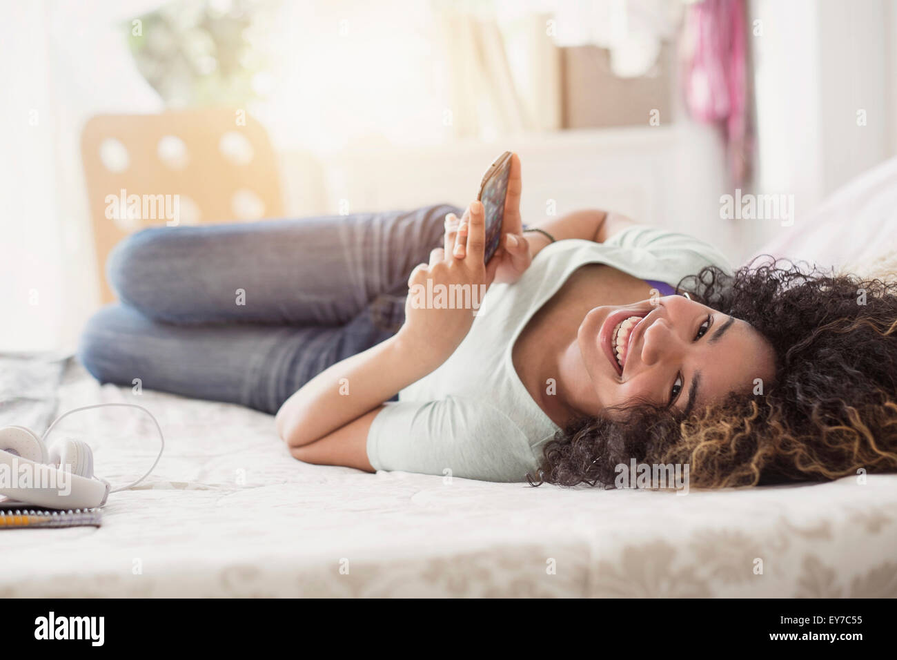 Ritratto di ragazza adolescente (16-17) texting in camera da letto Foto Stock