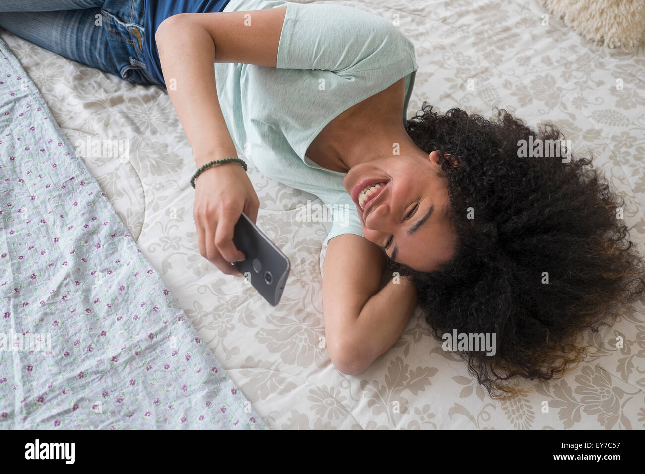 Ragazza adolescente (16-17) texting in camera da letto Foto Stock