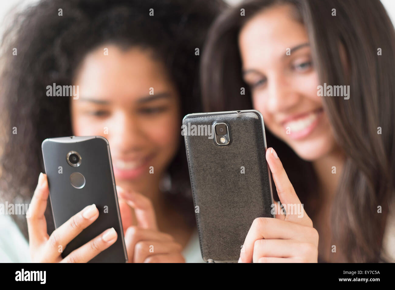 Le ragazze adolescenti (14-15, 16-17) utilizzando i telefoni intelligenti Foto Stock