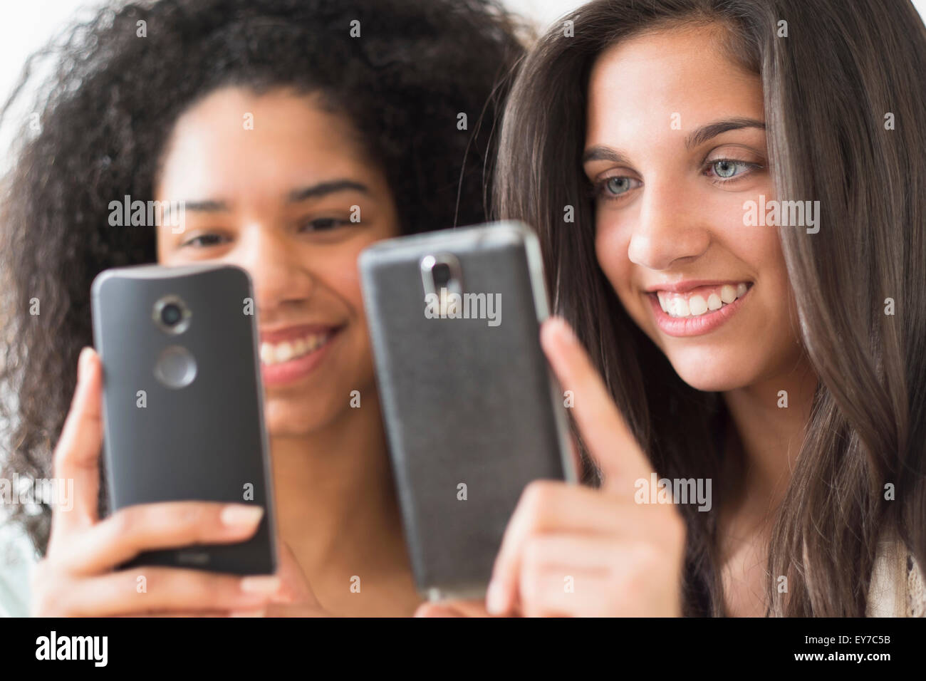 Le ragazze adolescenti (14-15, 16-17) utilizzando i telefoni intelligenti Foto Stock