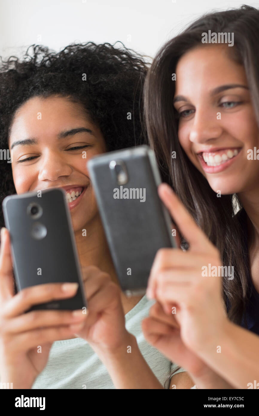 Le ragazze adolescenti (14-15, 16-17) utilizzando i telefoni intelligenti Foto Stock
