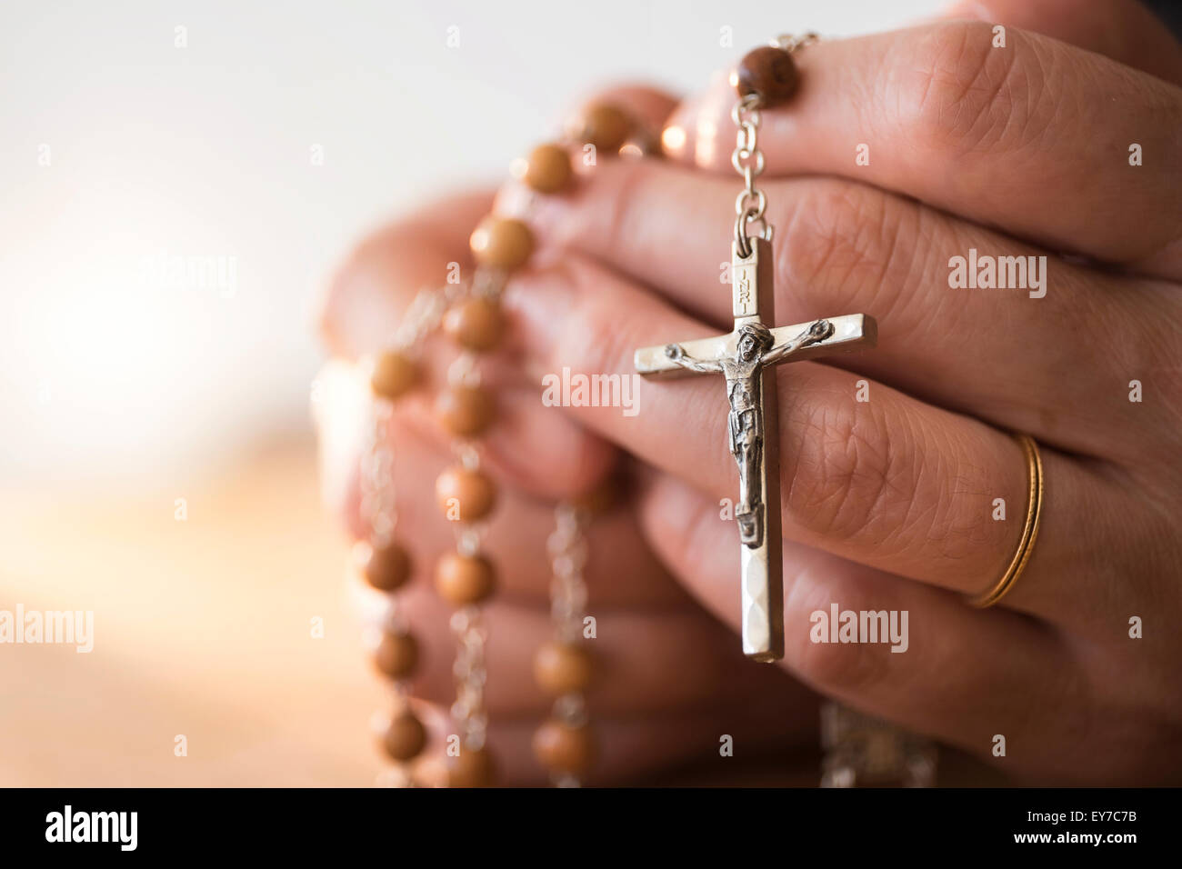 Donna che prega con il rosario in mano Foto Stock