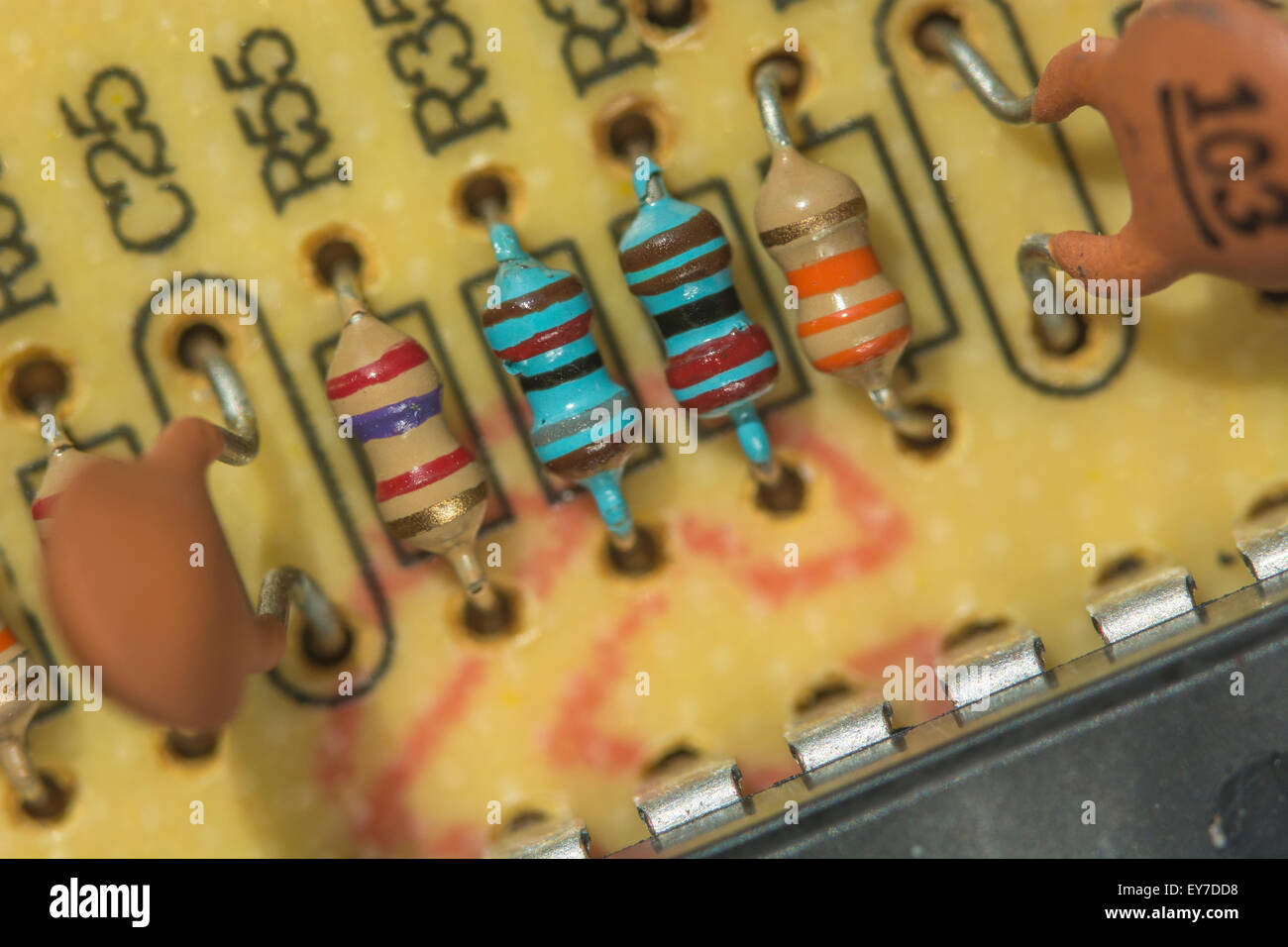 Macro-foto di resistori (carbonio e pellicola metallica [blu]) e condensatori su scheda a circuito stampato a foro passante. Concetto di resistenza, resistenza elettrica Foto Stock