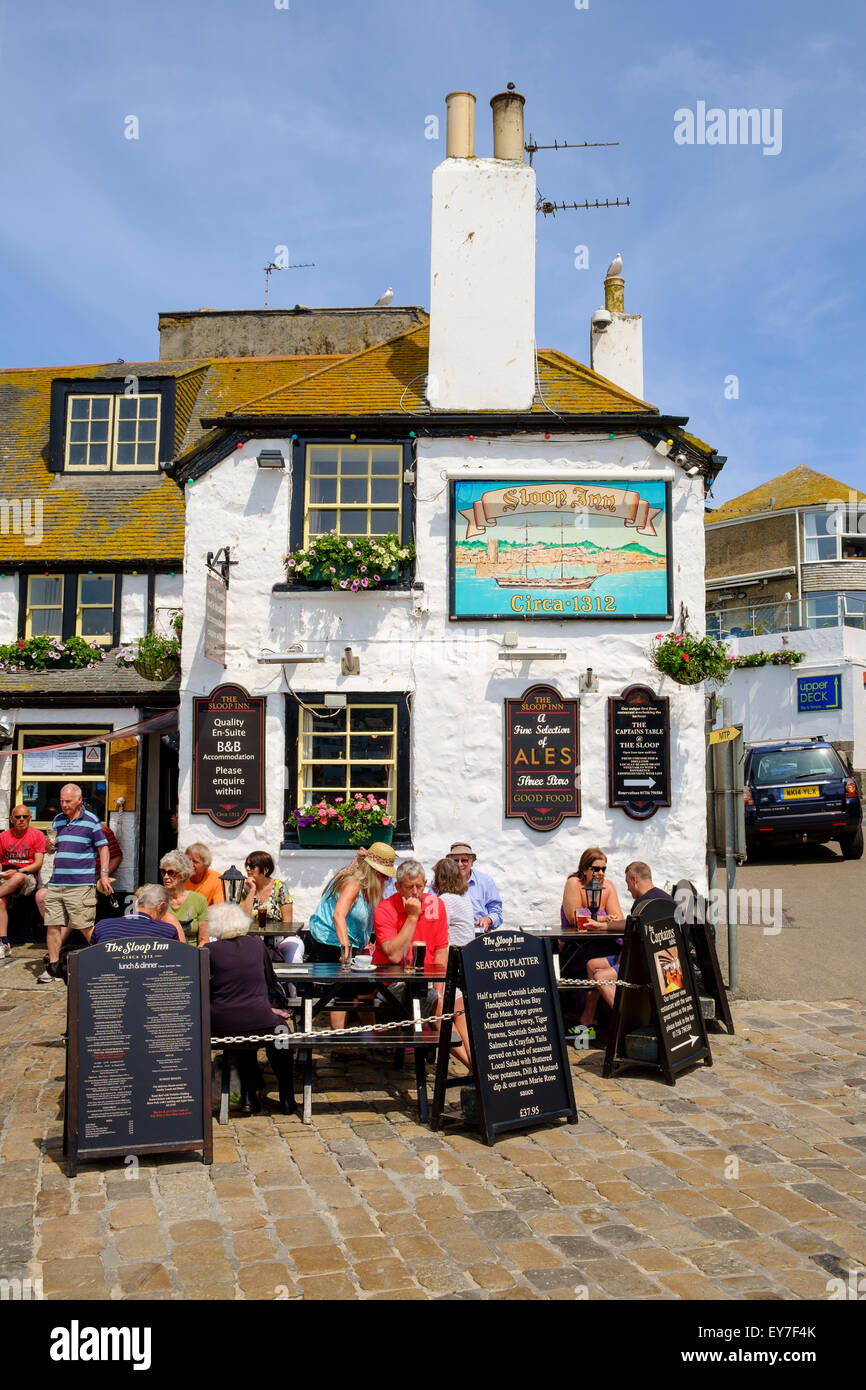 I turisti seduti fuori dalle antiche Sloop Inn pub al porto di St Ives, Cornwall, Inghilterra, Regno Unito in estate Foto Stock