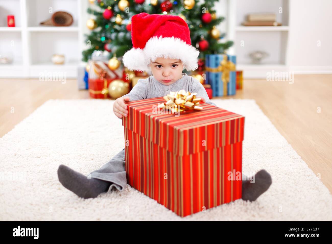 Piccolo Ragazzo seduto dietro il grande regalo di Natale box Foto Stock