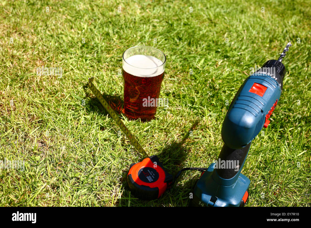 Strumenti di lavoro prevista sul prato con una pinta di bitter in estate Foto Stock