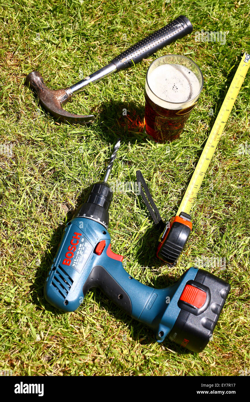 Strumenti di lavoro prevista sul prato con una pinta di bitter in estate Foto Stock