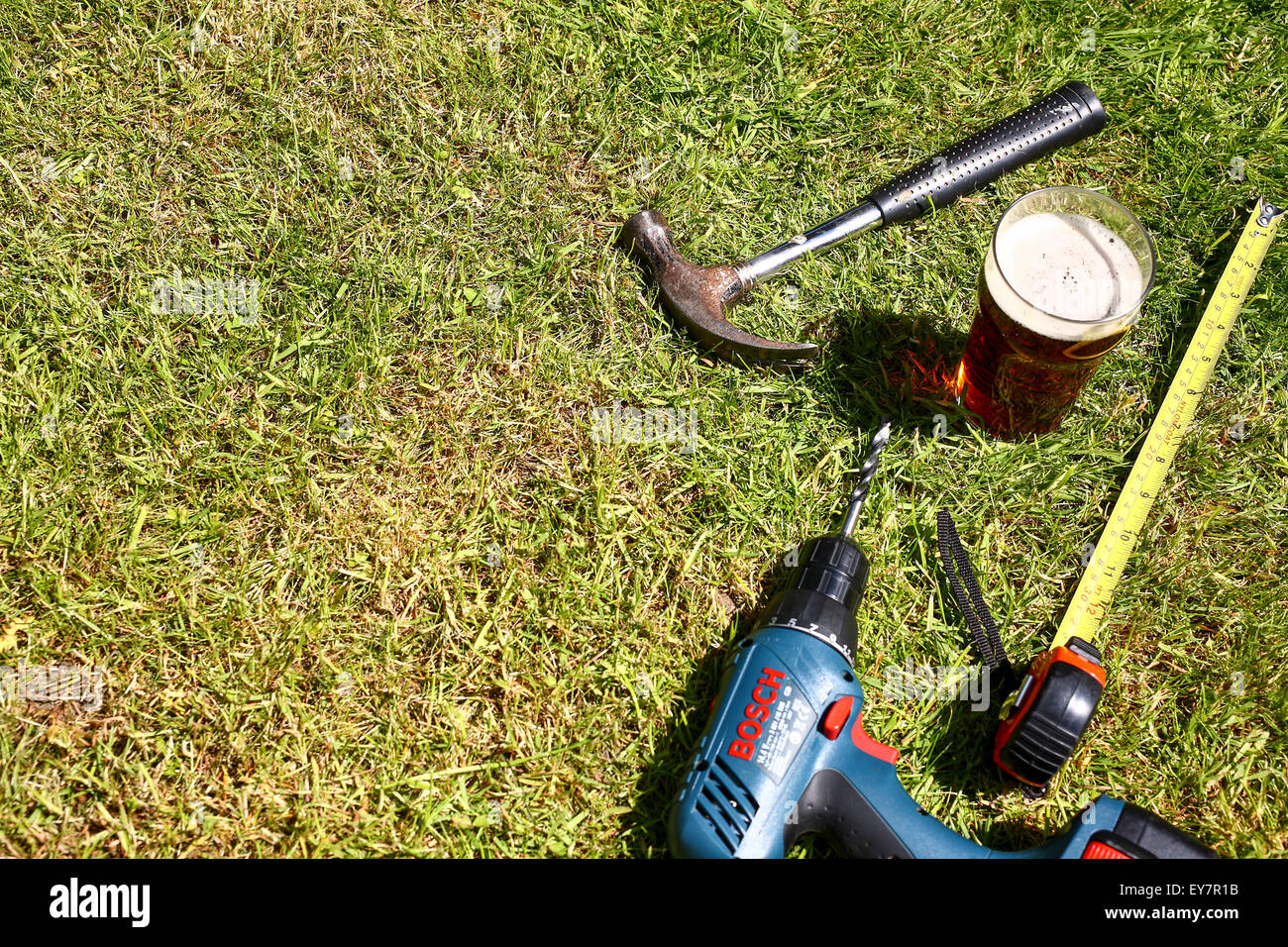 Strumenti di lavoro prevista sul prato con una pinta di bitter in estate Foto Stock