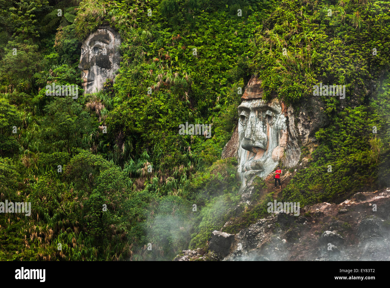 Un visitatore è avvistato vicino ad una formazione di faccia gigante che illustra il carattere del Toar (figura ancestrale) a Bukit Kasih, Sulawesi del Nord, Indonesia. Foto Stock
