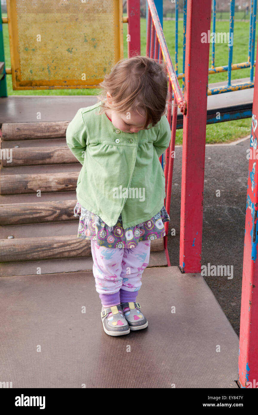 Bambina con le mani dietro la schiena, guardando verso di lei in nuove scarpe Foto Stock