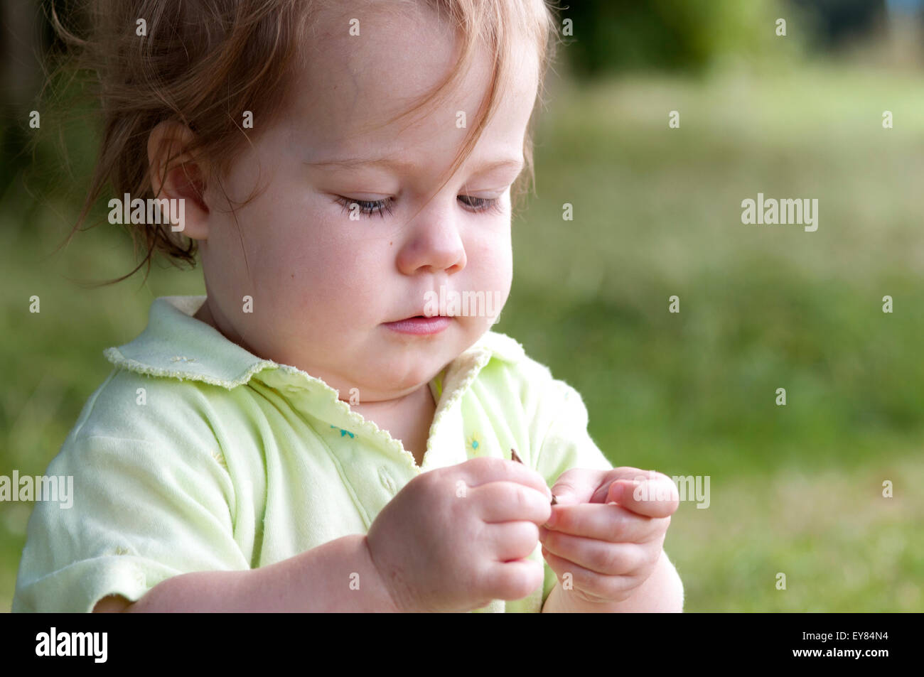Ritratto di una bambina guardando e giocando con una foglia Foto Stock