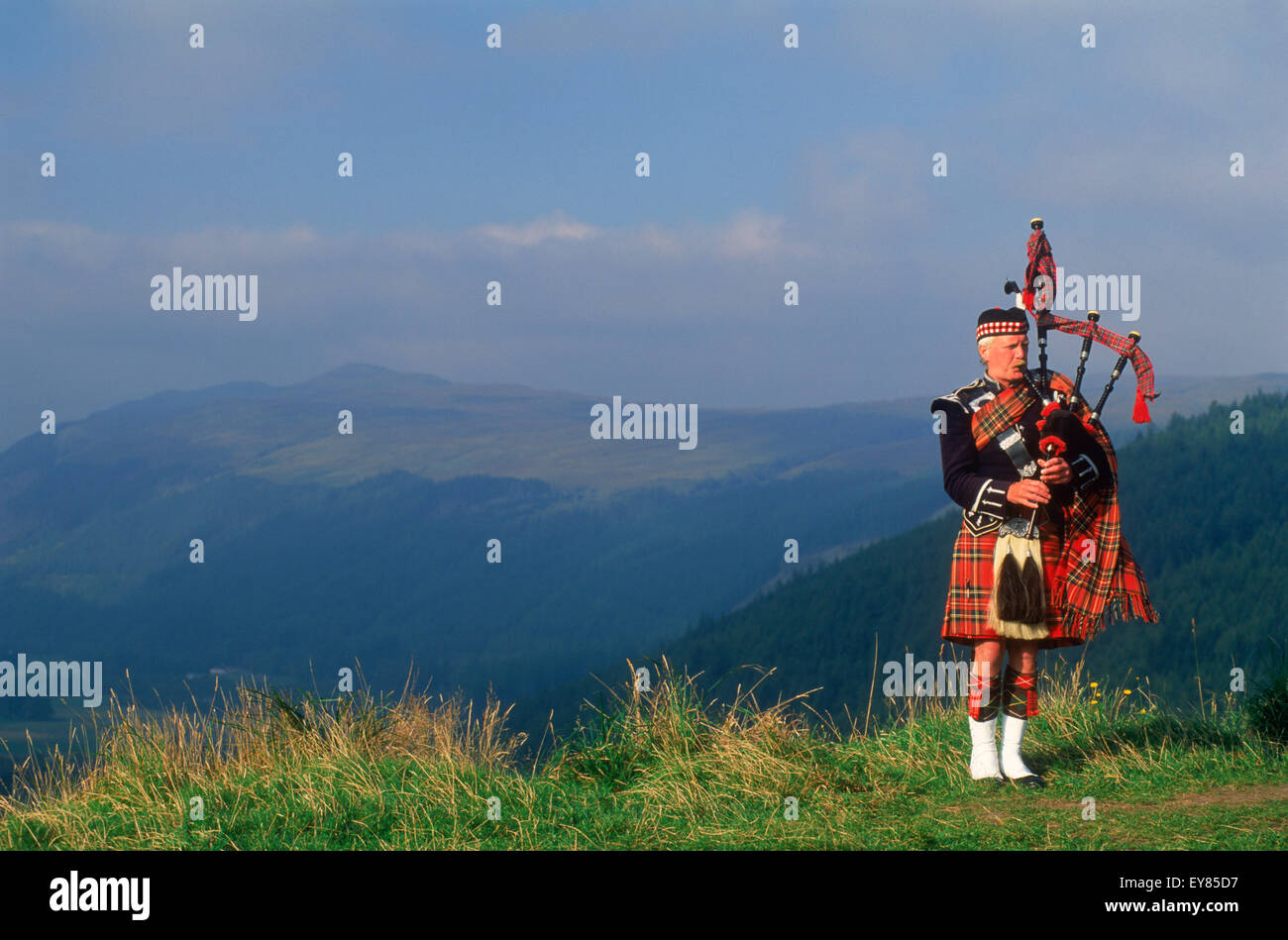 Bagpiper a Loch Ginestra nelle Highlands scozzesi Foto Stock