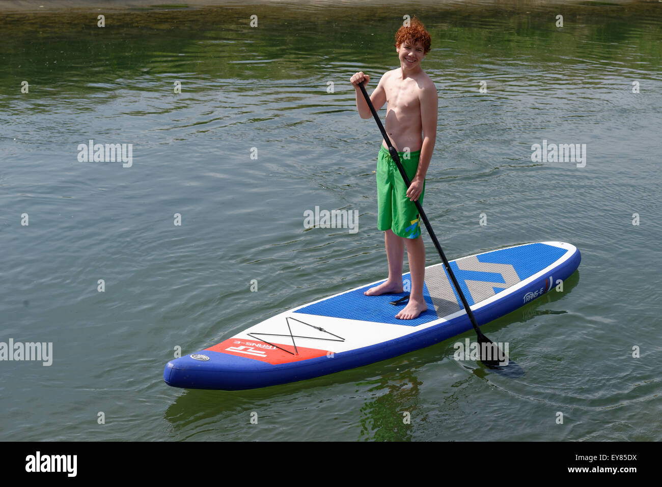 Ragazzo su una stand up board, stand up paddling, sulla Loisach canal, Alta Baviera, Baviera, Germania Foto Stock