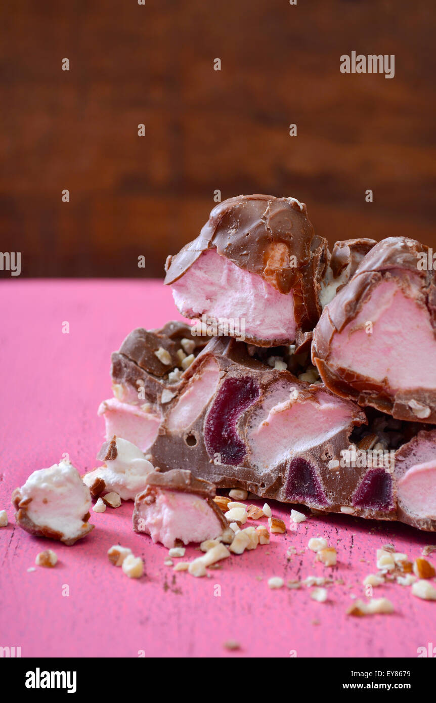 Primo piano della caramella al cioccolato con marshmallows, dadi e glace ciliegie su vintage rosa tavolo in legno con legno scuro dello sfondo. Foto Stock