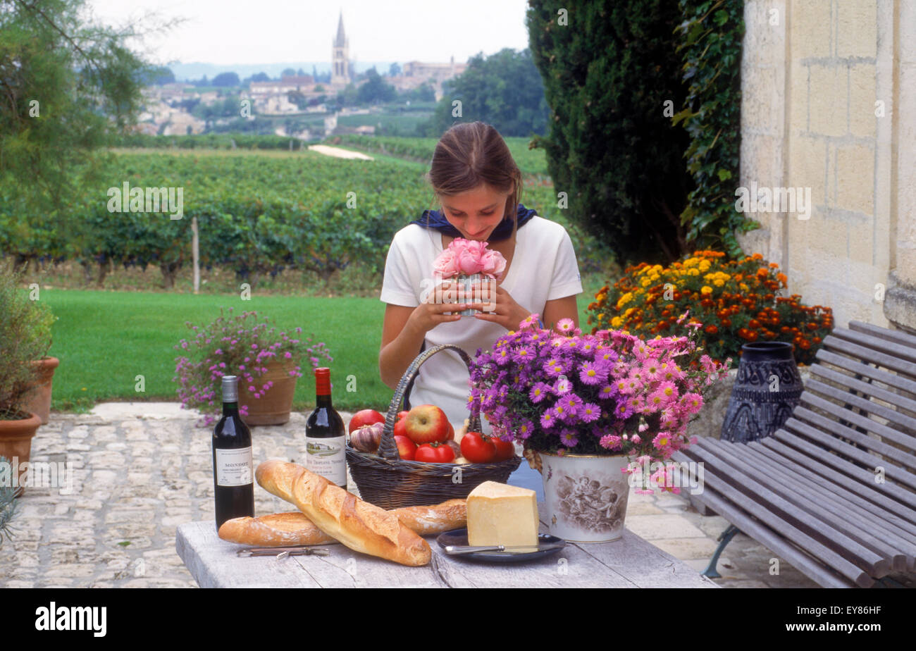 Signora giovane e vino francese, pane e formaggio circondato dai vigneti di Saint Emilion con villaggio chiesa steeple oltre Foto Stock