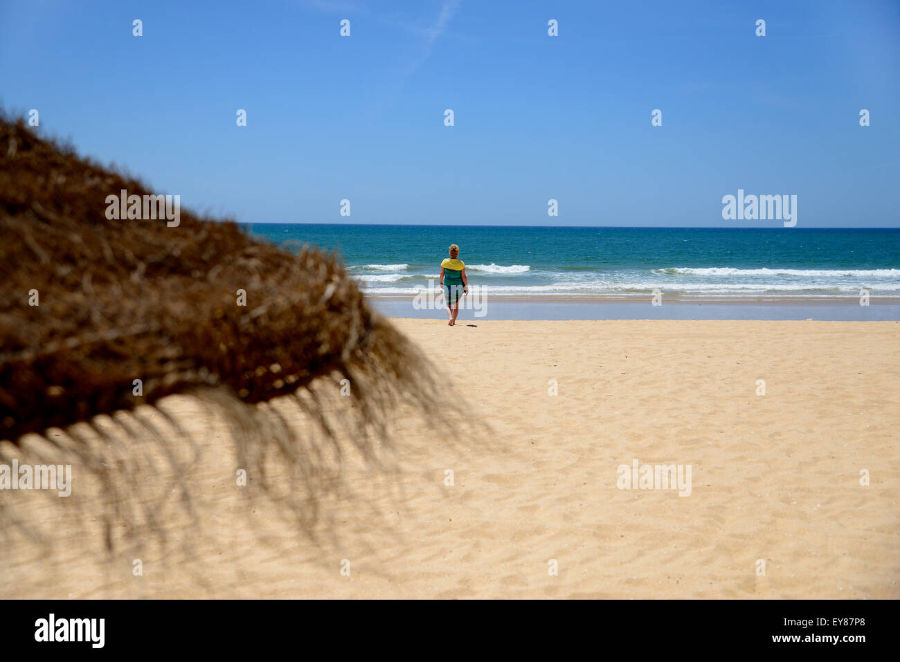 Signora sulla spiaggia di sabbia dorata con il blu del cielo e mare blu. Foto Stock