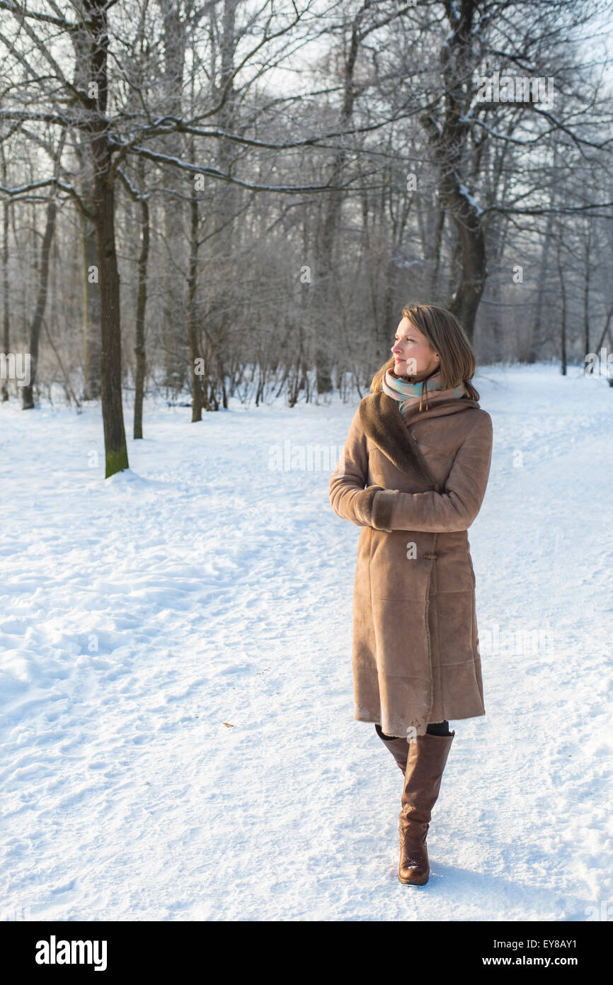 Giovane donna in cappotto passeggiate nel paesaggio invernale Foto Stock