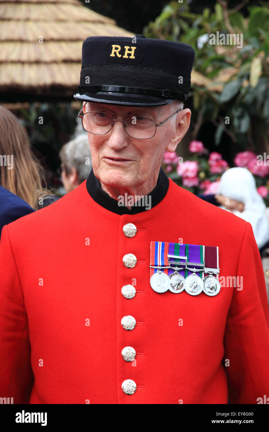 Un pensionato di Chelsea vestito nel suo cappotto rosso che indossa un Ospedale Reale di cappuccio e visualizzando il suo medaglie. Foto Stock