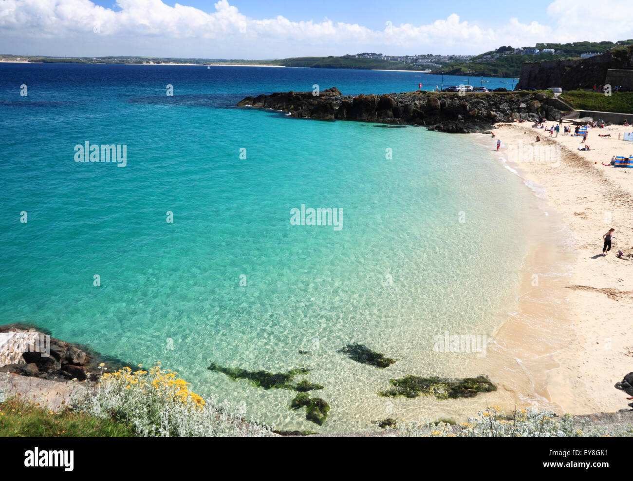 Una sabbiosa spiaggia della Cornovaglia con acqua turchese e le rocce in primo piano. Foto Stock