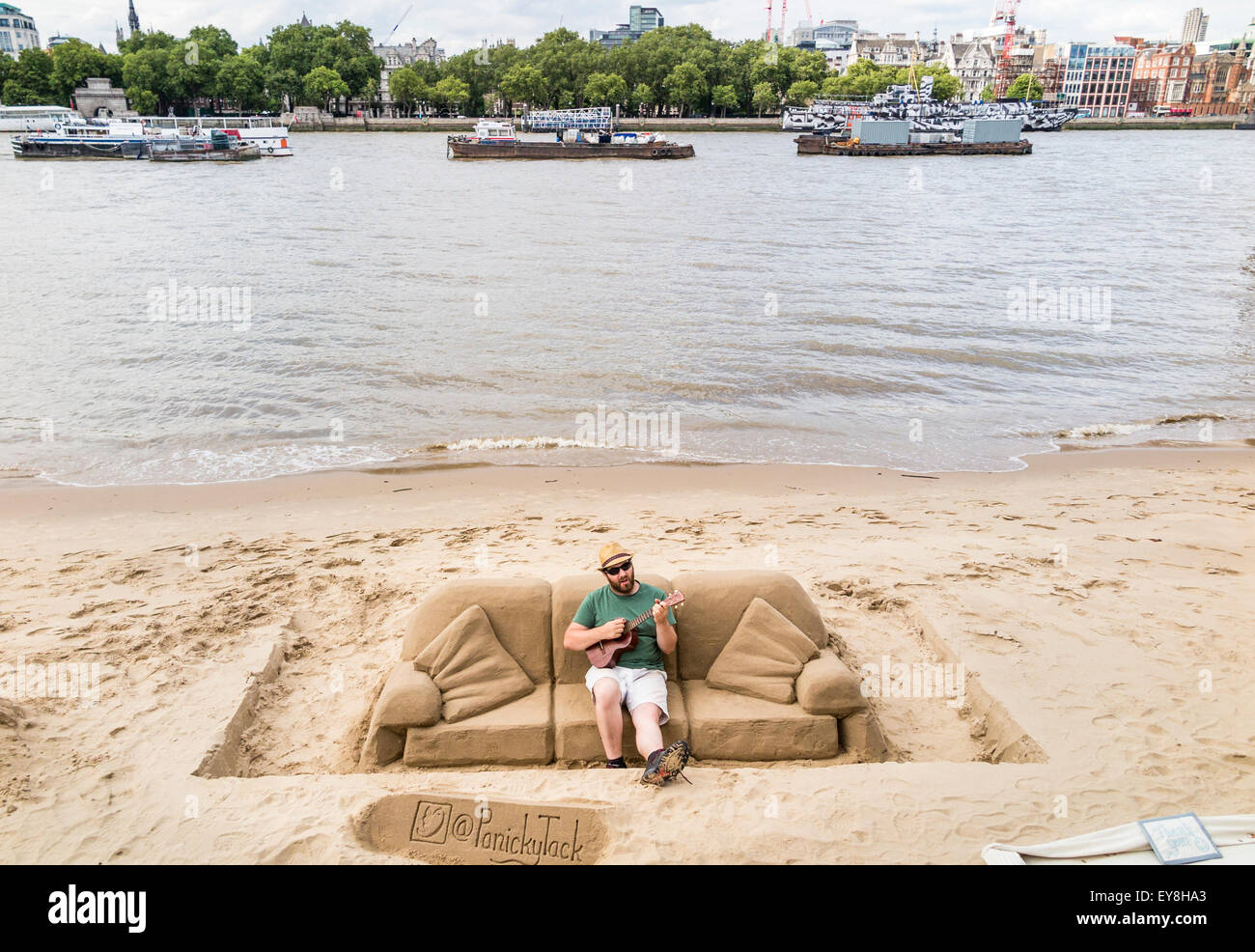 Scultore di sabbia, rendendo le sculture per suggerimenti, suonando una chitarra su un divano di sabbia, South Bank del terrapieno, London, Regno Unito Foto Stock