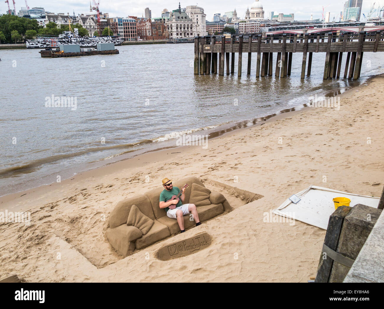 Scultore di sabbia, rendendo le sculture per suggerimenti, suonando una chitarra su un divano di sabbia, South Bank del terrapieno, London, Regno Unito Foto Stock