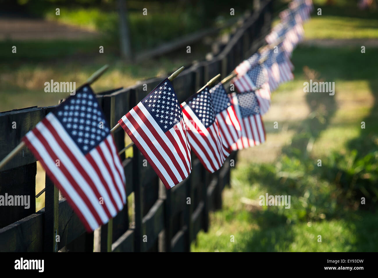 Nero recinzione in legno trailing off con piccole bandiere noi appesi da ogni post; Stati Uniti d'America Foto Stock