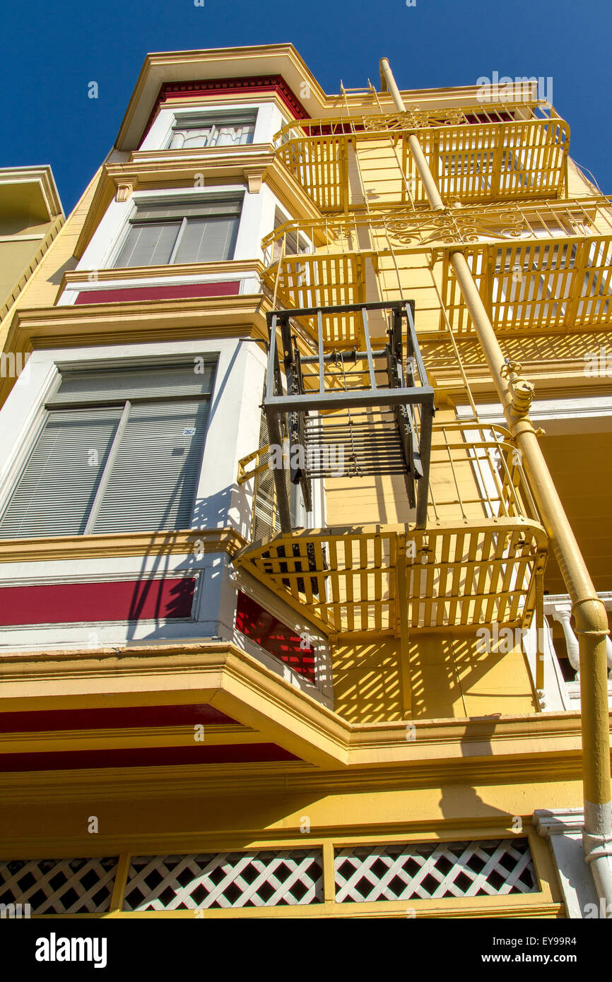 Casa dipinta di giallo con una fuga esterna di ferro sul lato esterno dell'edificio nel quartiere di Telegraph Hill di San Francisco, California Foto Stock