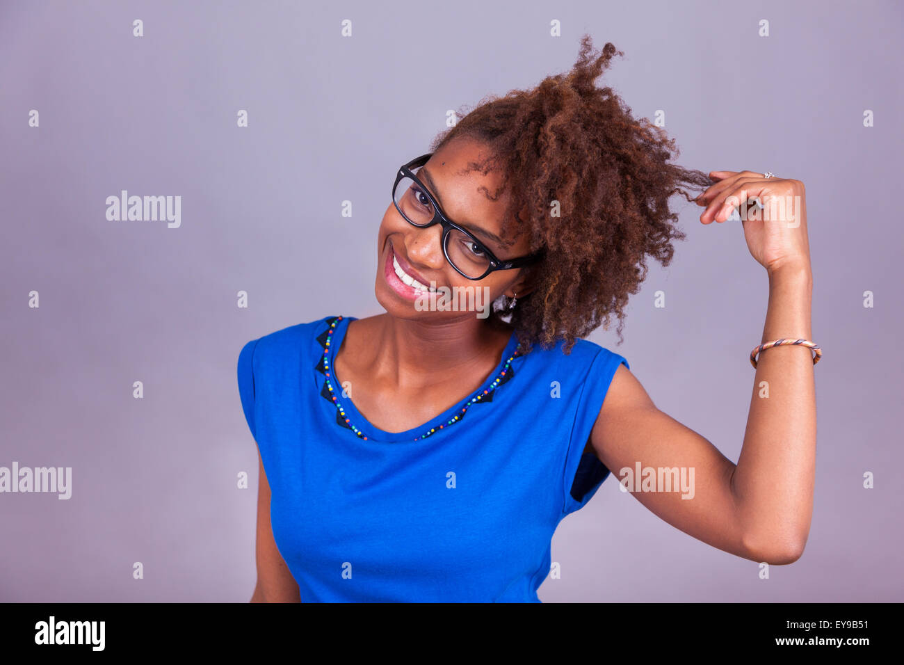 Giovane africano donna americana tenendo le sue frizzy capelli afro - gente nera Foto Stock