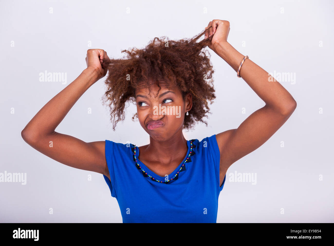 Giovane africano donna americana tenendo le sue frizzy capelli afro - gente nera Foto Stock