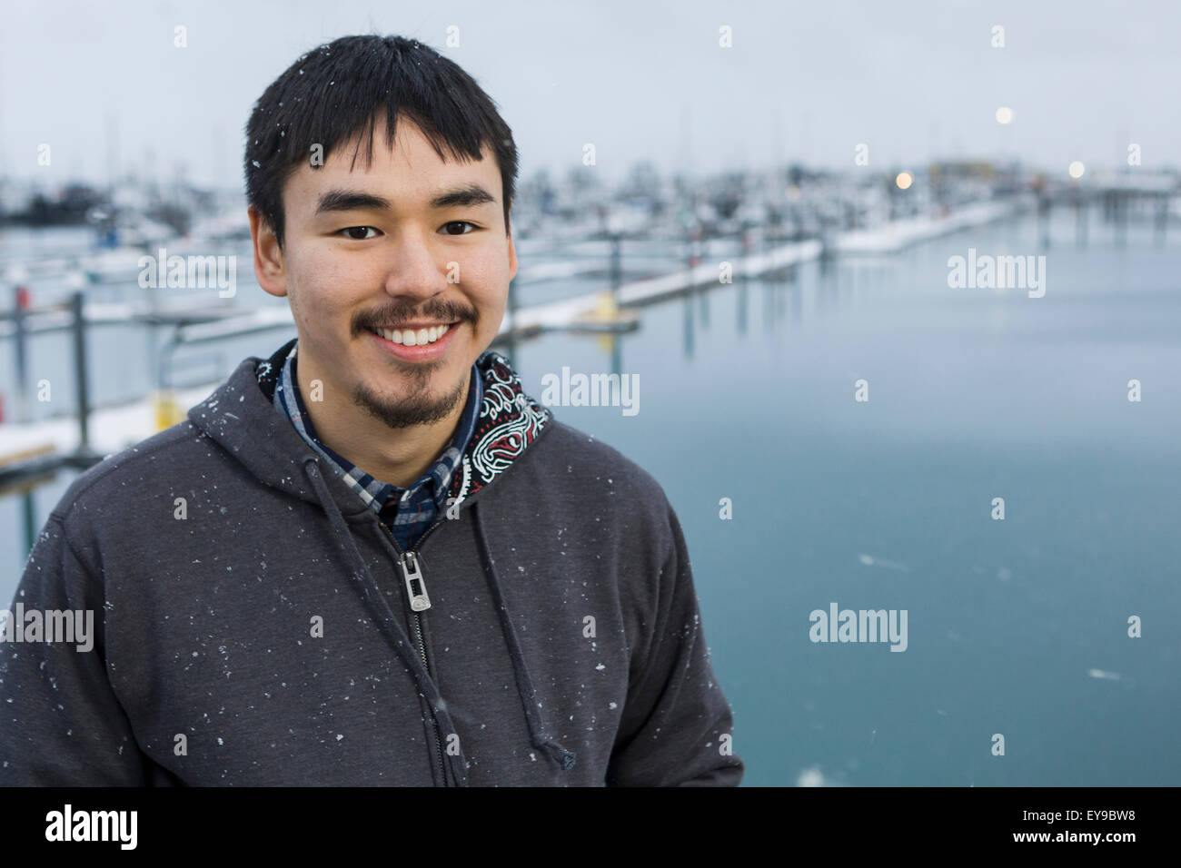 Ritratto di un Alaskan uomo nativo di fronte all'omero piccola barca porto, Homer Spit, centromeridionale Alaska Foto Stock