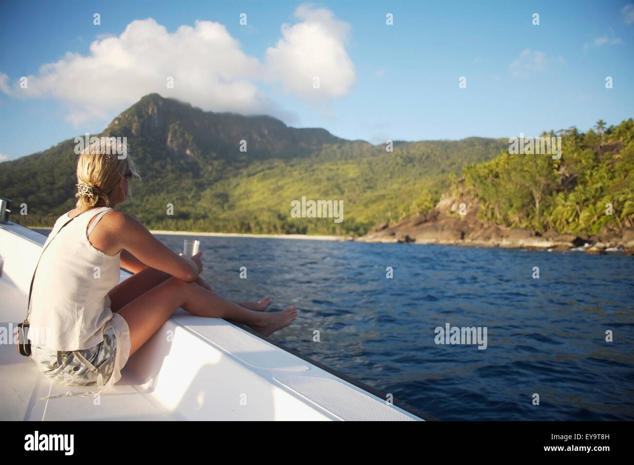 Donna seduta sul lato della barca verso Isola Foto Stock