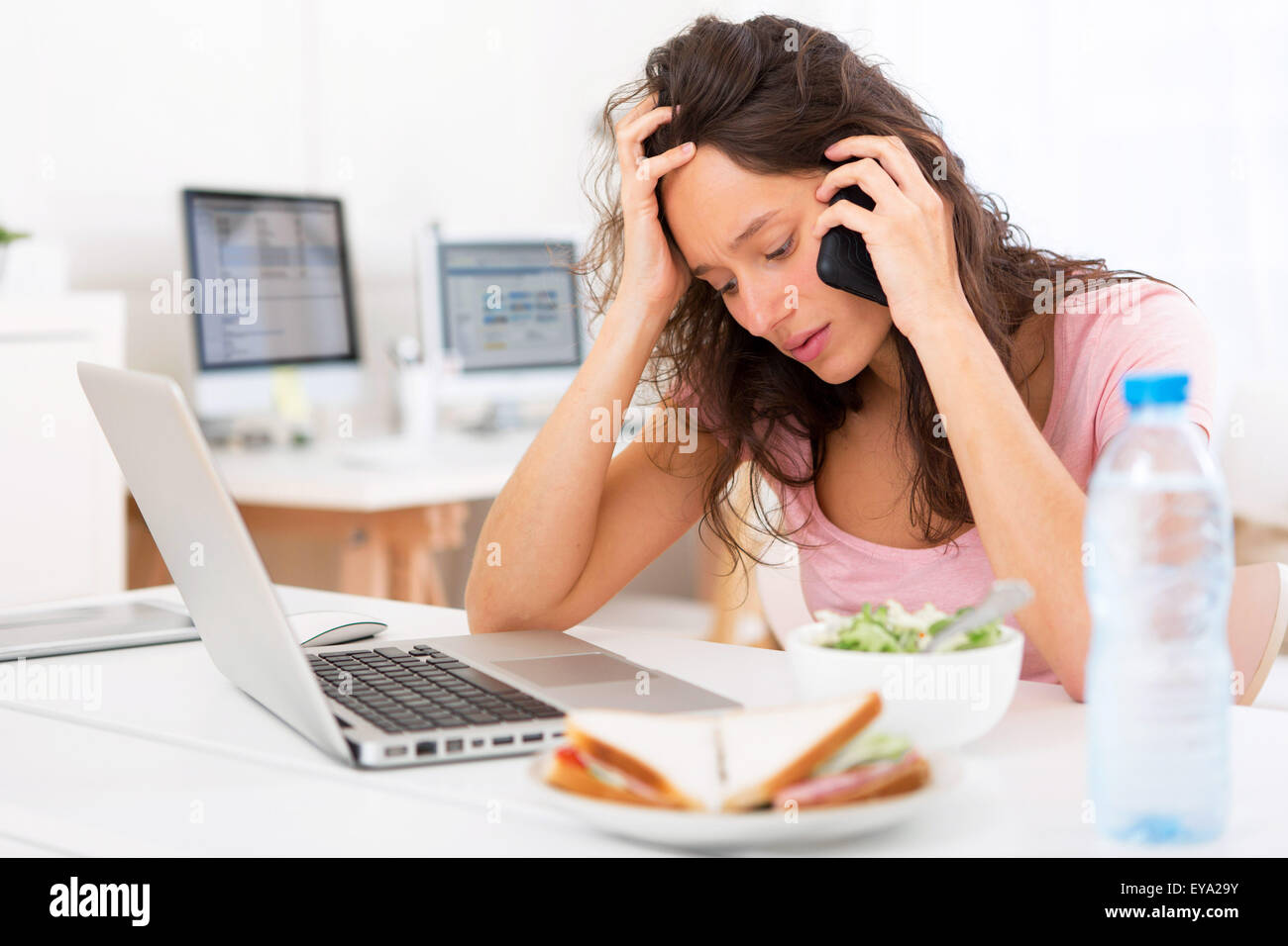 Vista di un giovane studente attraente insalata mangiare mentre si telefona Foto Stock