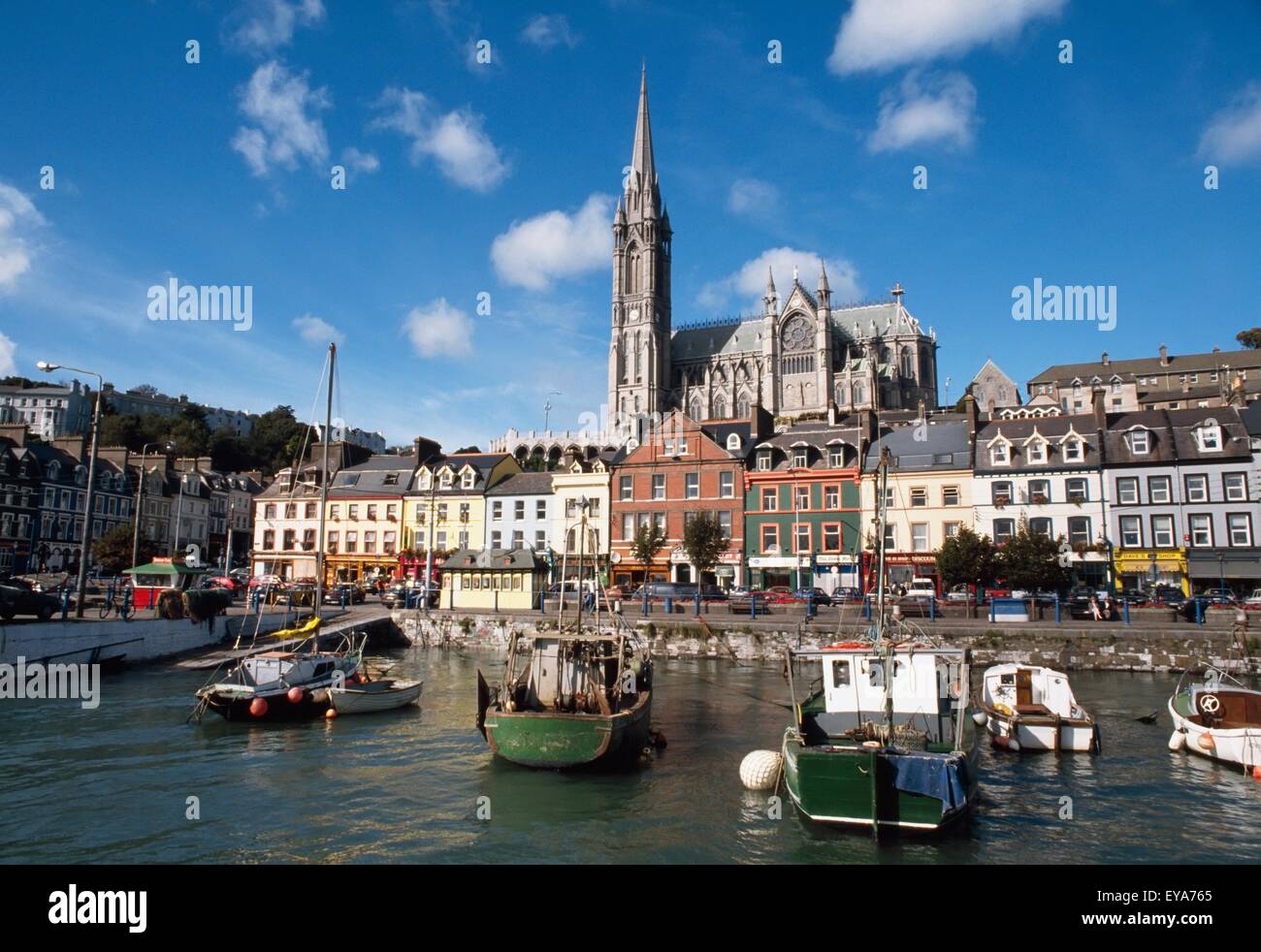 Cobh, Co Cork, Irlanda; vista delle barche da pesca in porto con una vista di San Colman's Cathedral Foto Stock