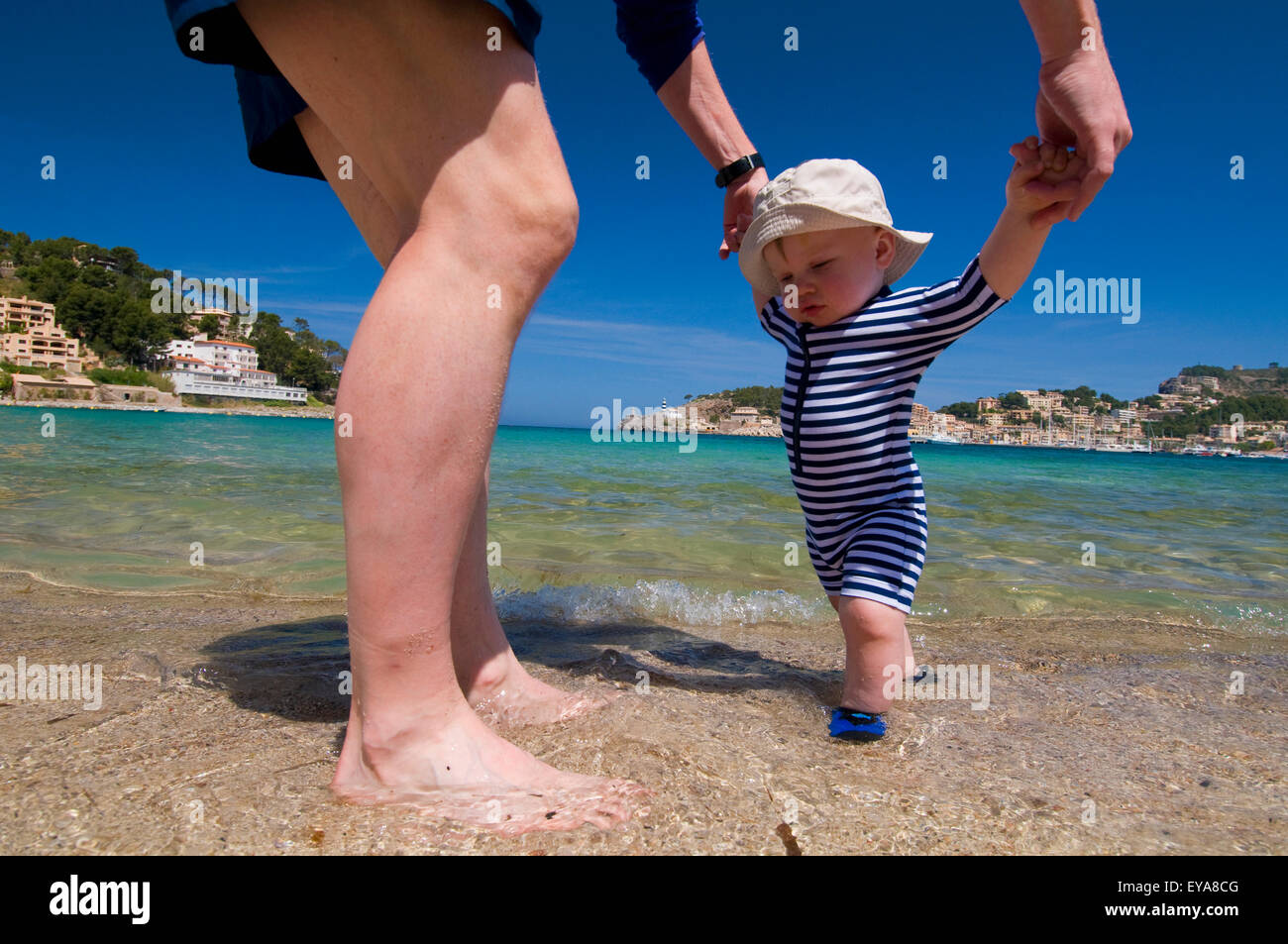 Padre aiutando Baby Boy (6-11 mesi) a piedi sulla spiaggia, Soller,Mallorca,Isole Baleari,Spagna Foto Stock