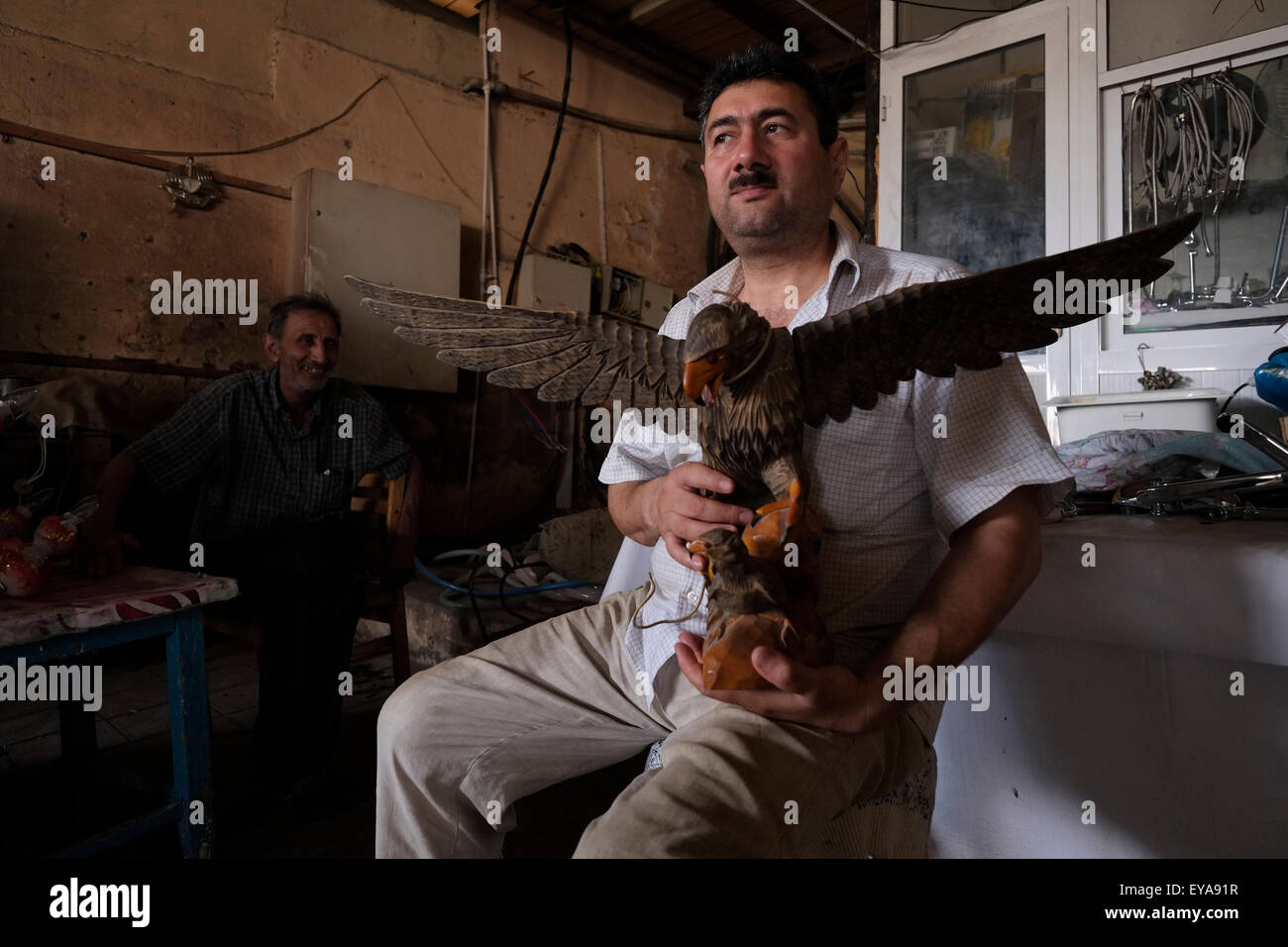 Un venditore detiene una figura scolpita di un'aquila Mercato di Taza Bazaar nella città di Baku in Azerbaigian Foto Stock