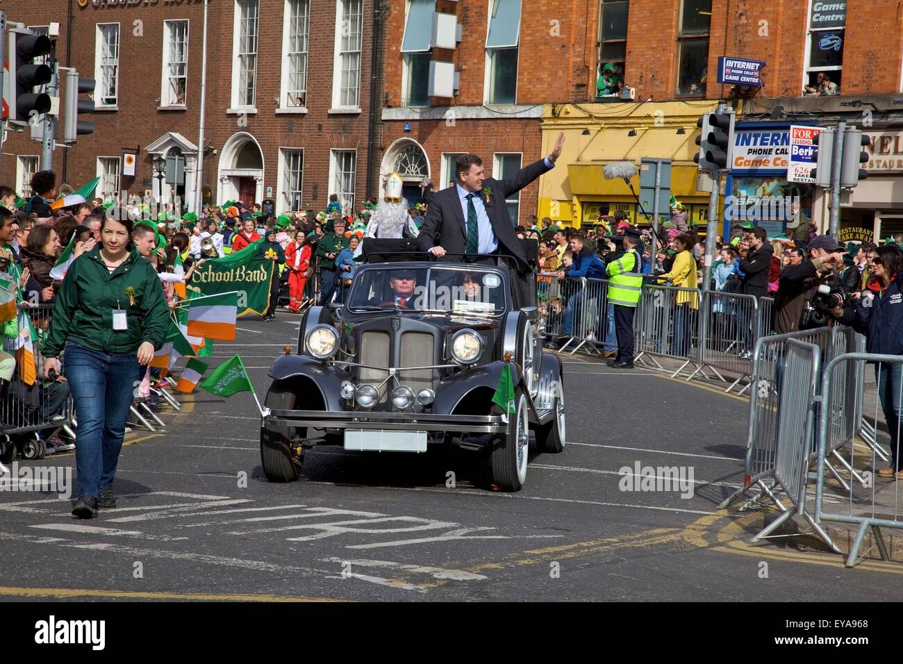 Dublino, Irlanda; un uomo onde da una vettura in movimento come si va in giù O'connell Street come parte di una sfilata Foto Stock