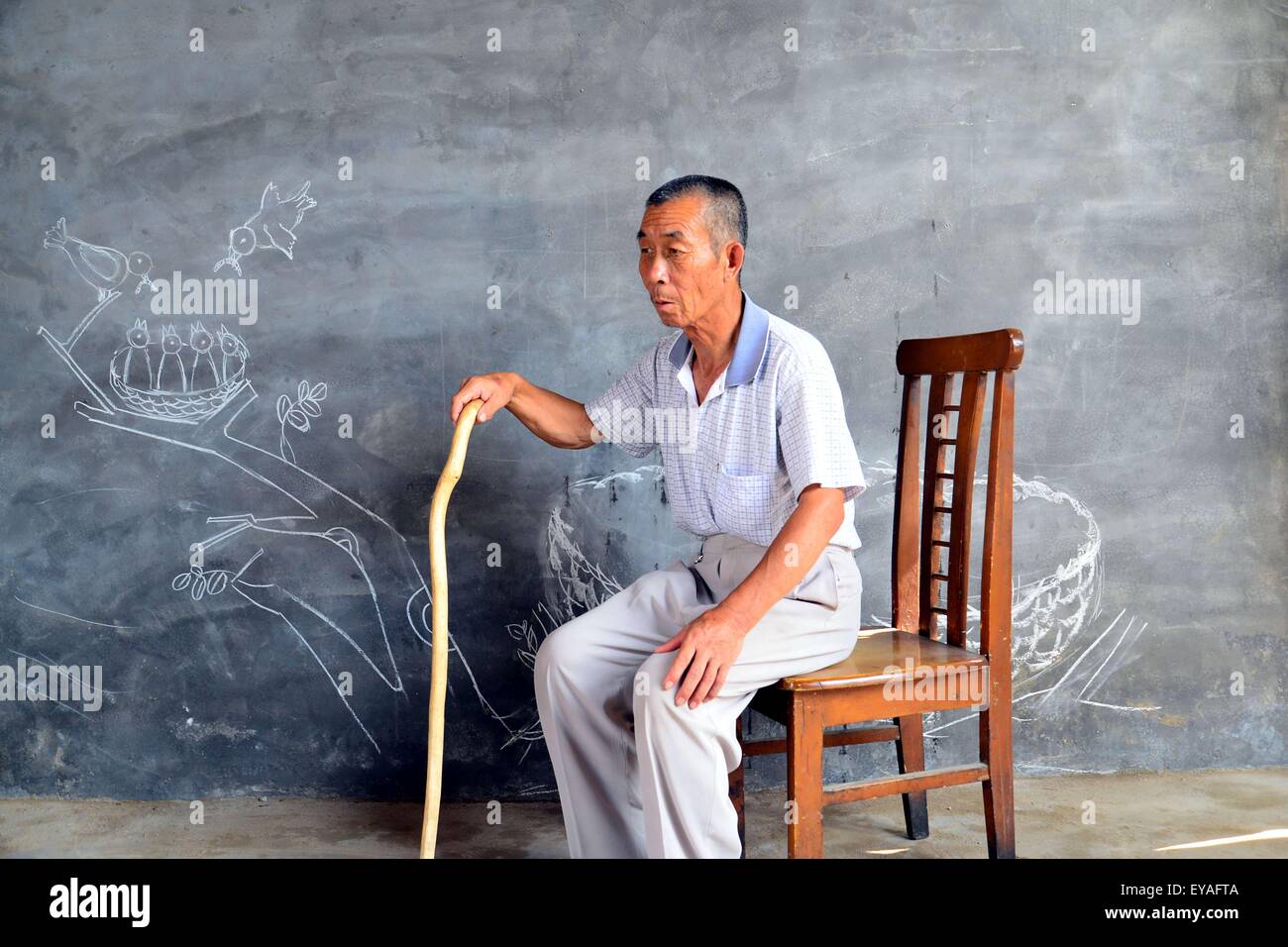 Liaocheng, la Cina della provincia dello Shandong. Xxv Luglio, 2015. Un vecchio uomo vuole ottenere insieme con i suoi figli nel villaggio Suanzili di Xiaozhuang County, est della Cina di Provincia di Shandong, 25 luglio 2015. Studenti del college dall'Accademia di Belle Arti di Liaocheng University è venuto a visitare la "sinistra" dietro i bambini e 'vuoto-nest" le persone anziane, aiutarli ad esprimere il loro desiderio per il ricongiungimento familiare con dipinti. © Zhao Yuguo/Xinhua/Alamy Live News Foto Stock