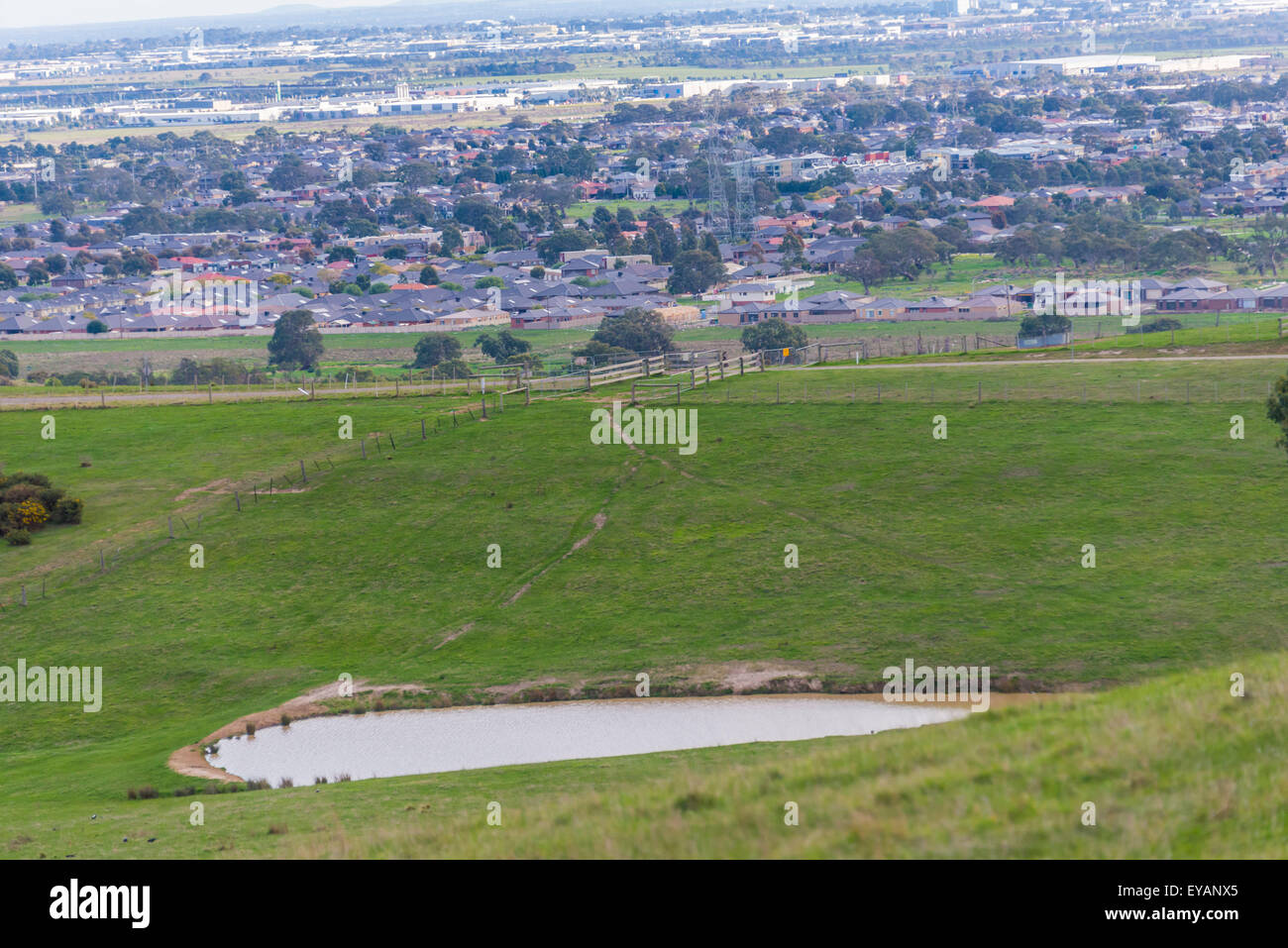 Melbourne periferia a distanza con i campi e terreni agricoli a ribalta con una diga waterhole. contrasto e sviluppo Foto Stock