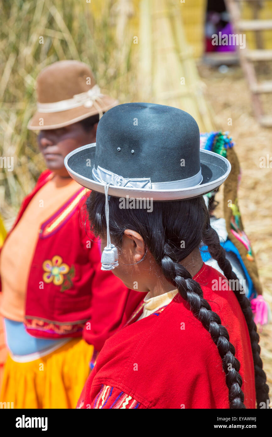 Isole galleggianti, il lago Titicaca, Puno, Perù. Donna locale con trecce indossando un tradizionale black bowler hat su Isla Apu Inti Foto Stock