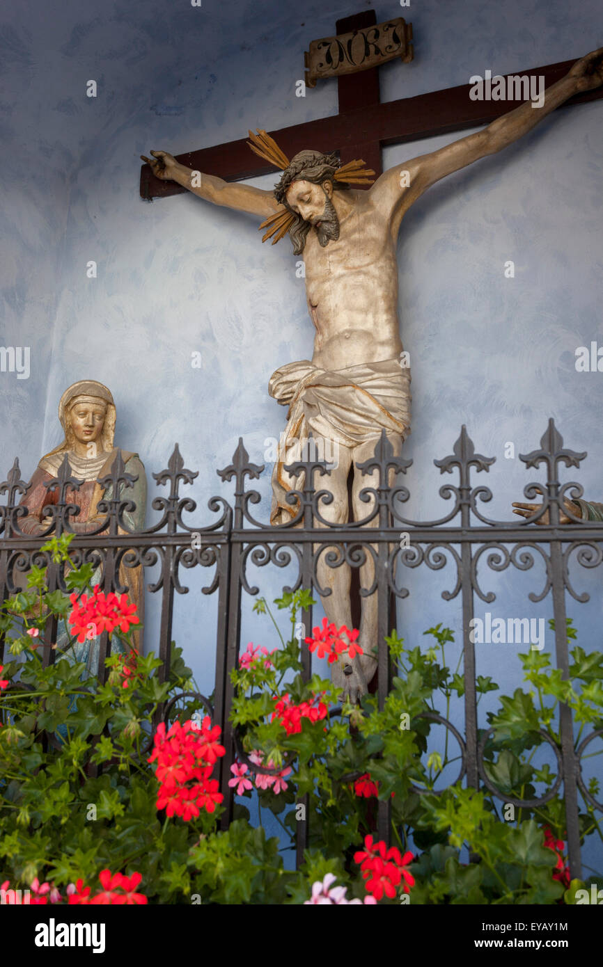 Statua della Vergine Maria e Gesù sulla Croce nella piccola cappella rurale, Cesky Krumlov Repubblica Ceca Pelargonium fiori Foto Stock