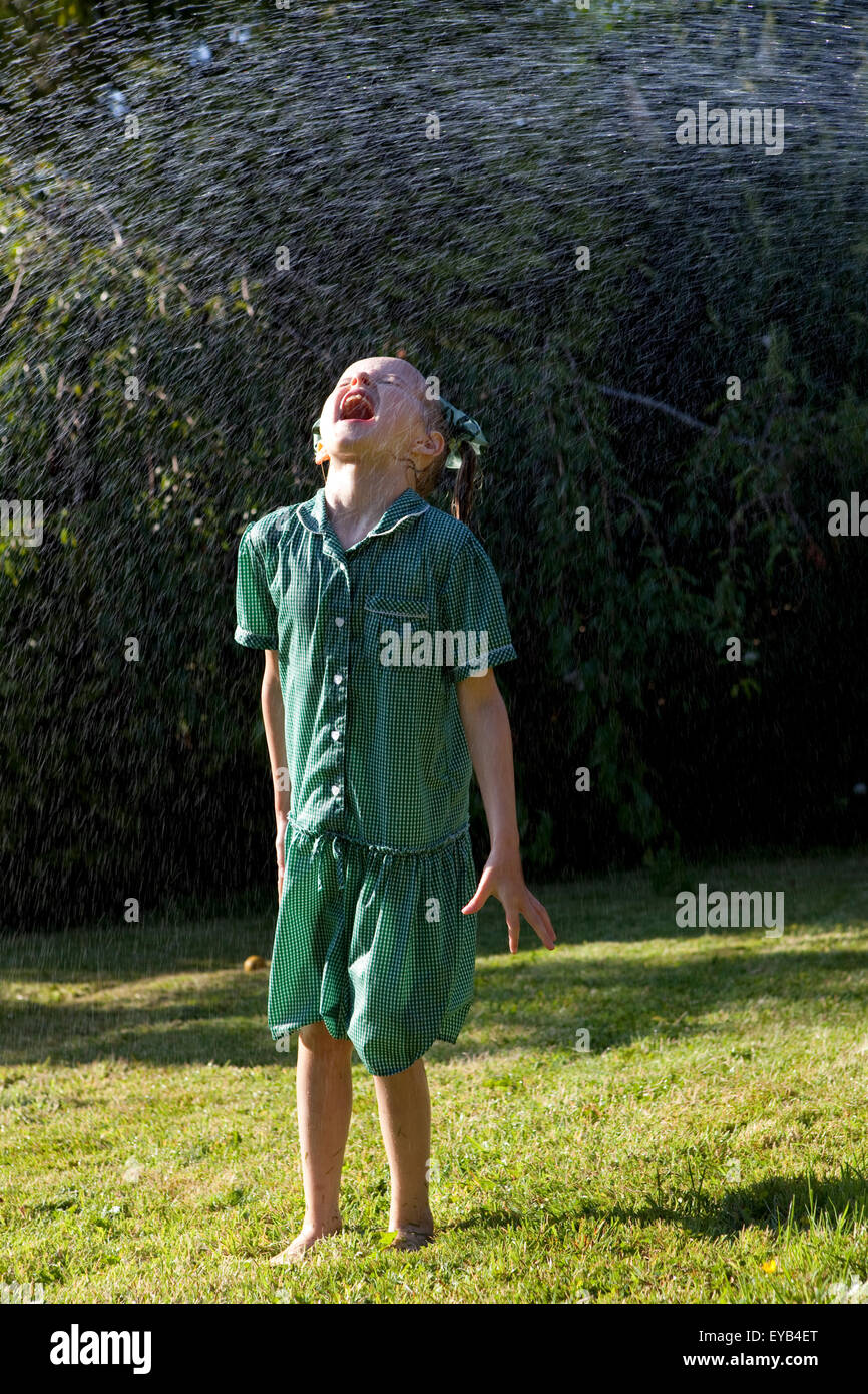 Ragazza in abito verde giocando in un soffione di erogazione dell'acqua. Foto Stock