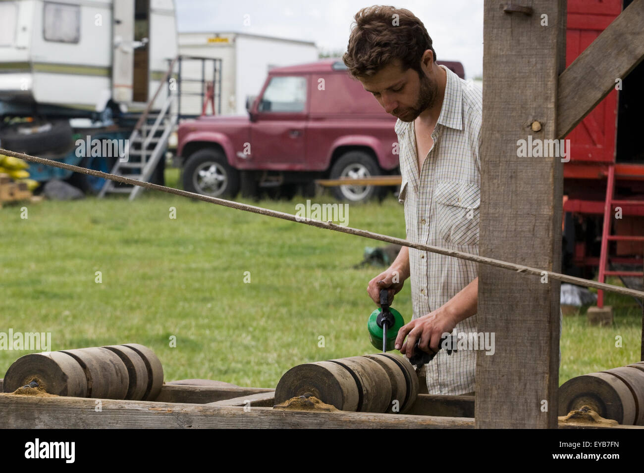 L'uomo lubrificando i rulli di legno su una sega da legno lama Mulino azionato da un motore di trazione Foto Stock
