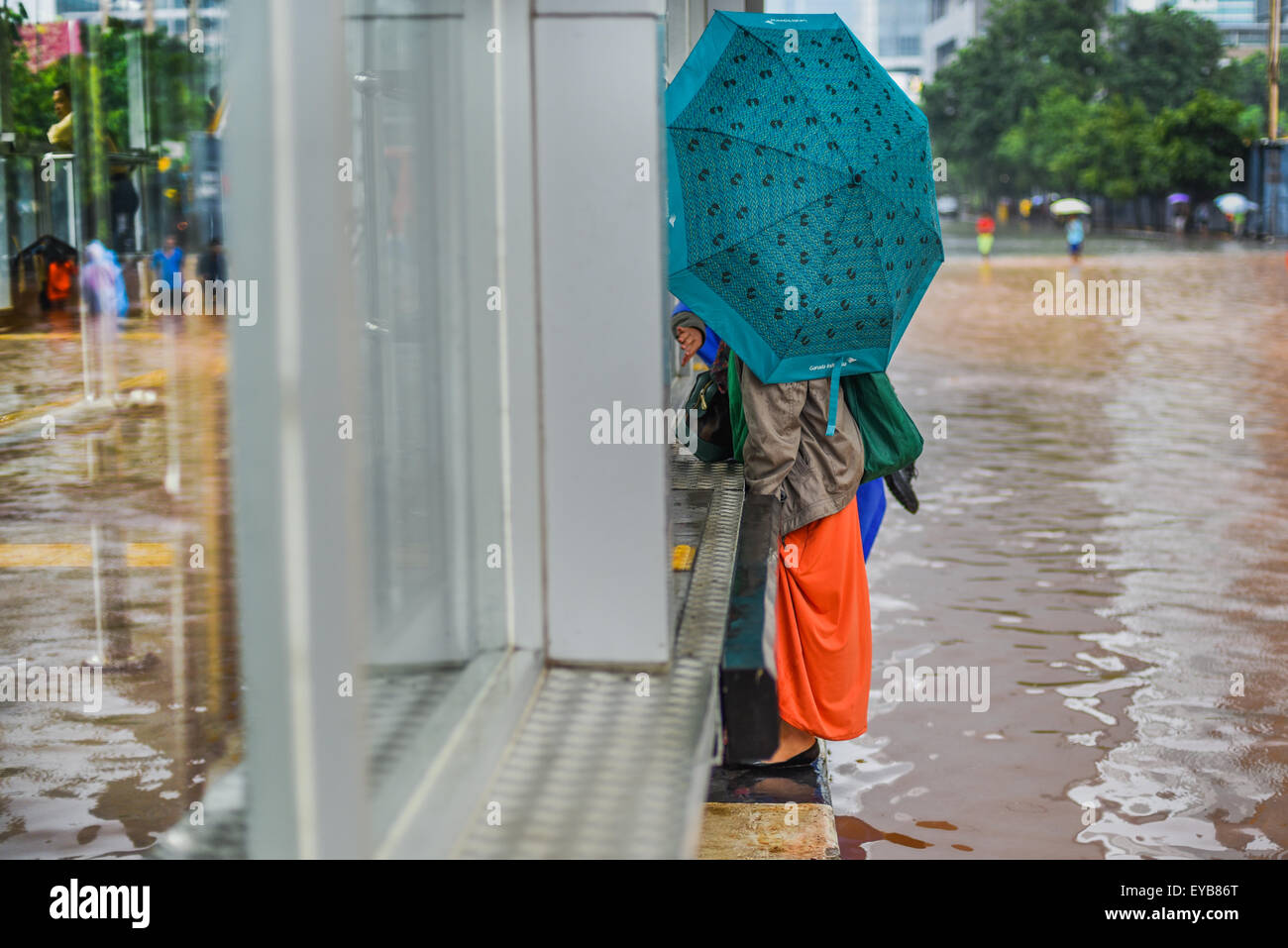 I pedoni cercano di evitare le acque alluvionali in Thamrin Street, Jakarta, dopo una pioggia continua ha lasciato l'area del centro della capitale indonesiana allagata. Foto Stock