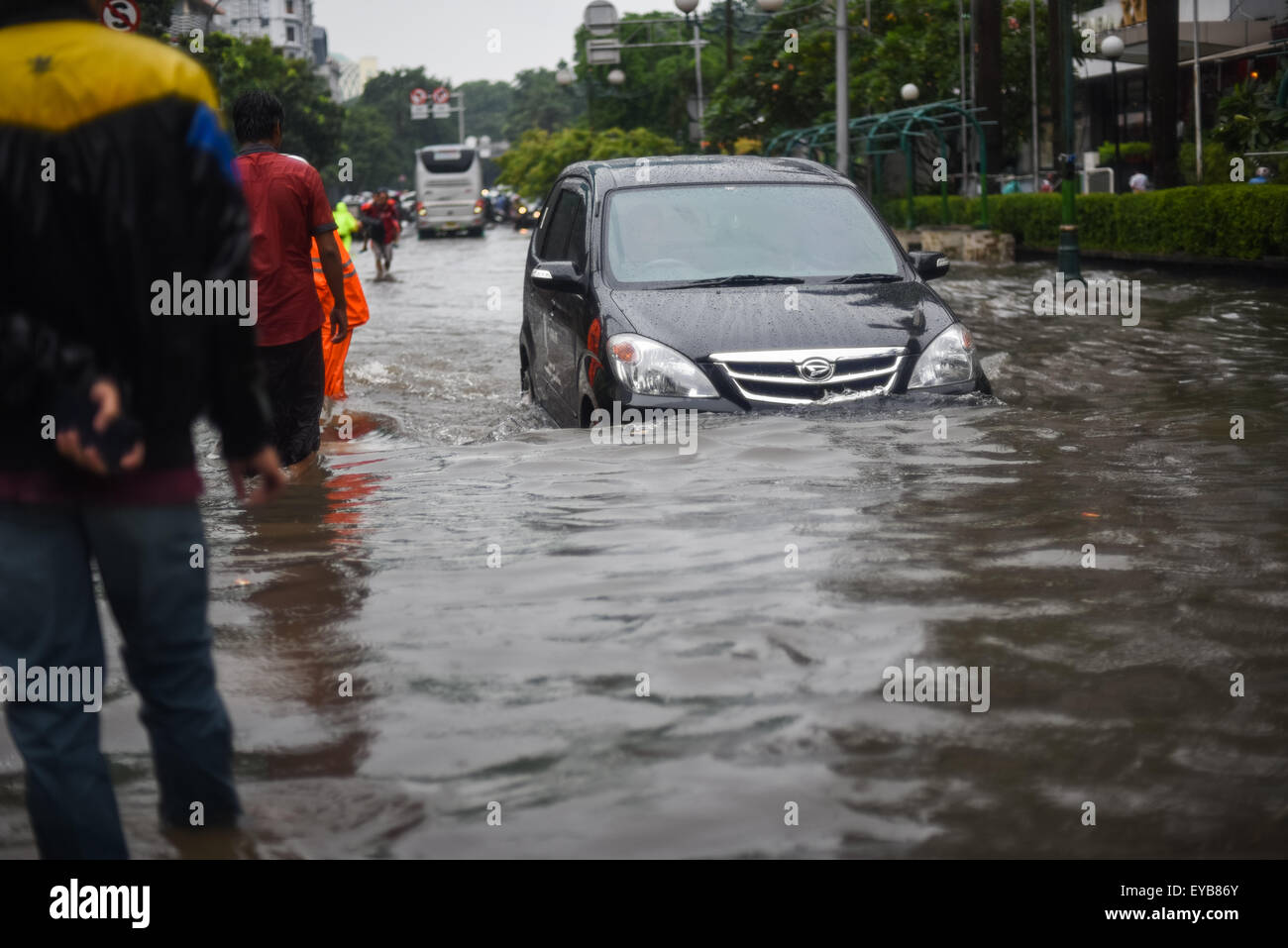 Un'auto che si muove attraverso una strada allagata, dopo una pioggia continua ha lasciato l'area del centro di Jakarta allagato. Foto Stock