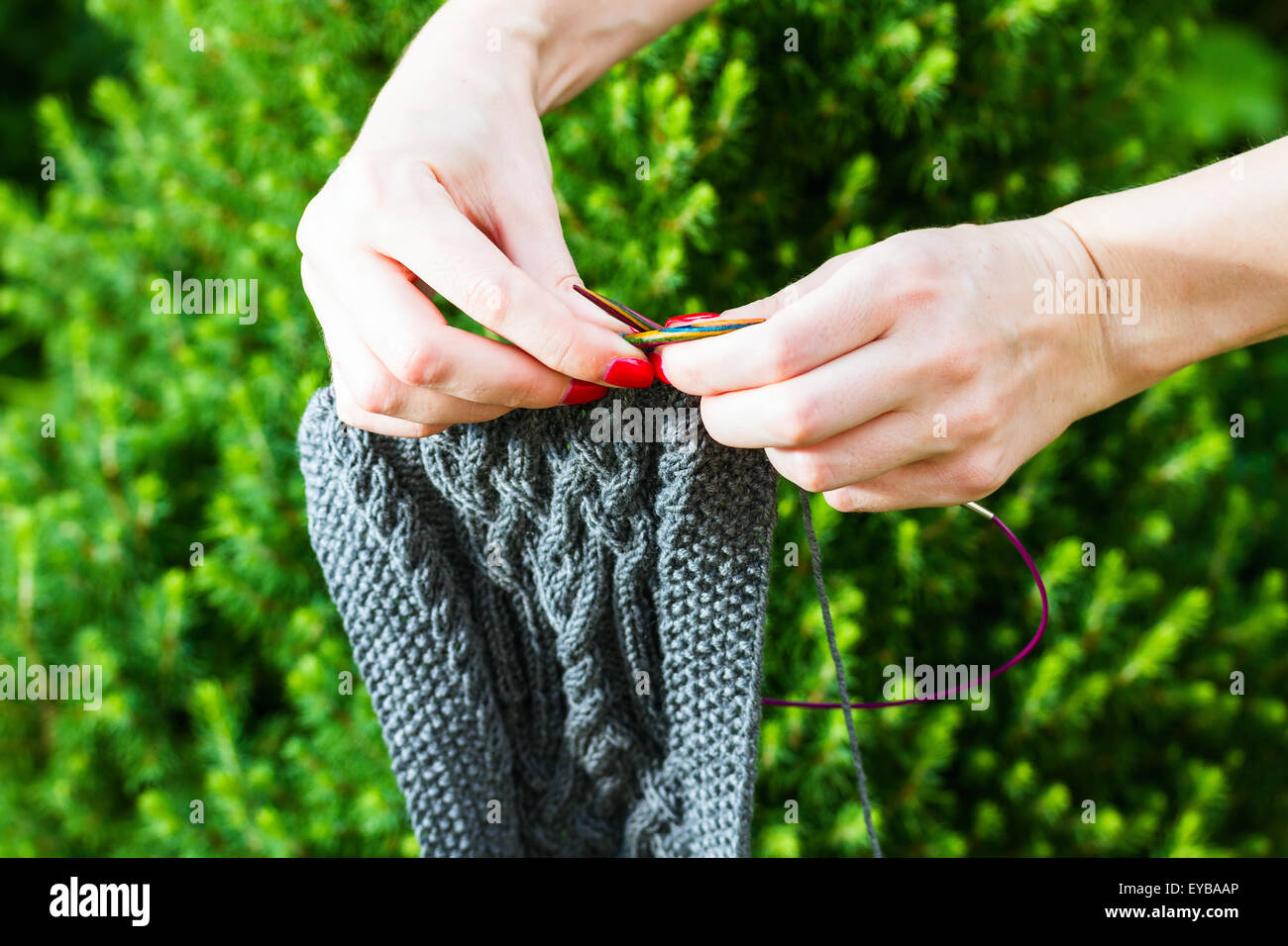 Fatte a mano sciarpa di lana e mani femminili in abete bianco sullo sfondo Foto Stock