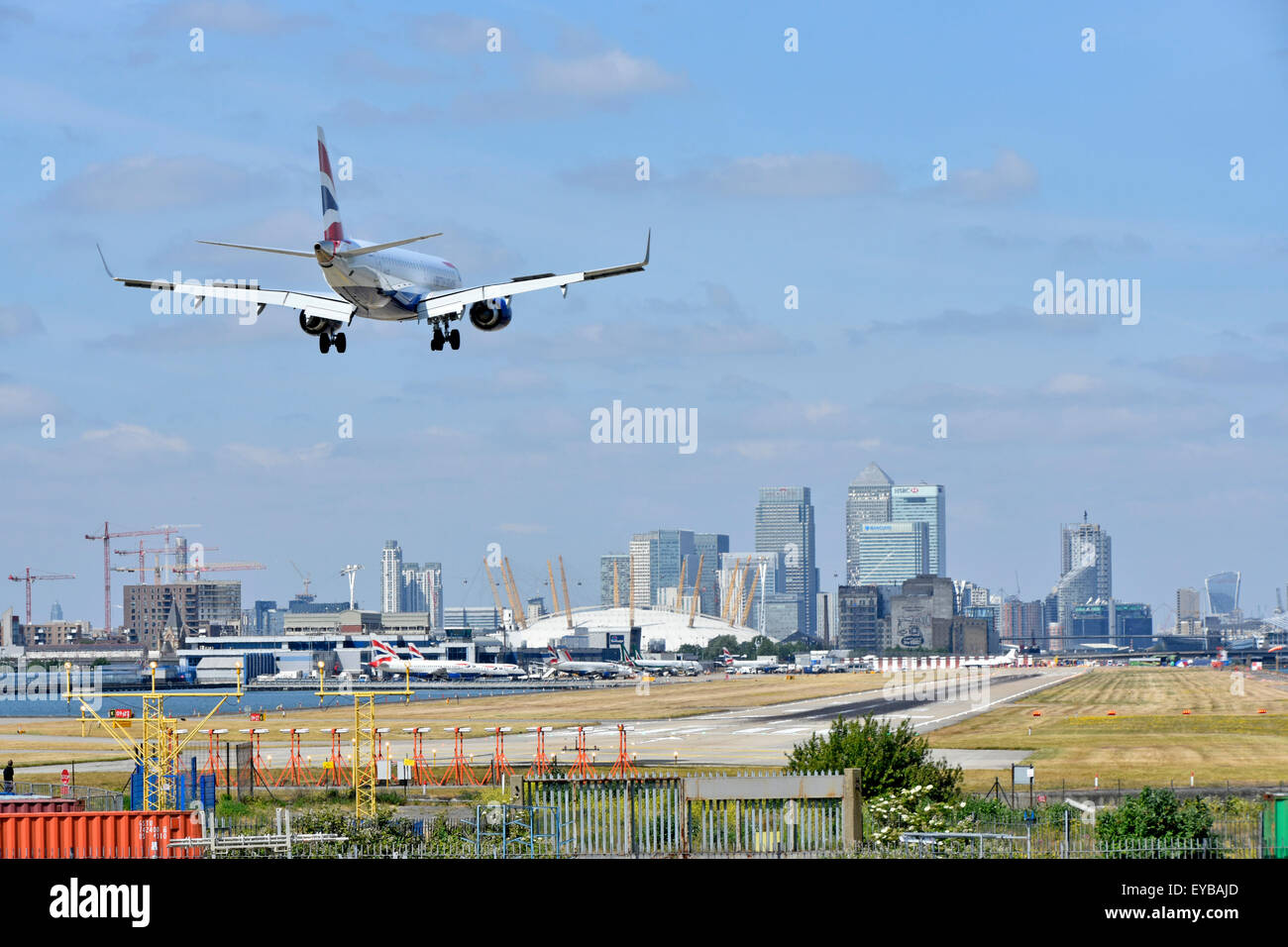 Volo British Airways in atterraggio a London City Airport (Newham) con l'O2 Arena e Canary Wharf (Tower Hamlets) skyline al di là Foto Stock
