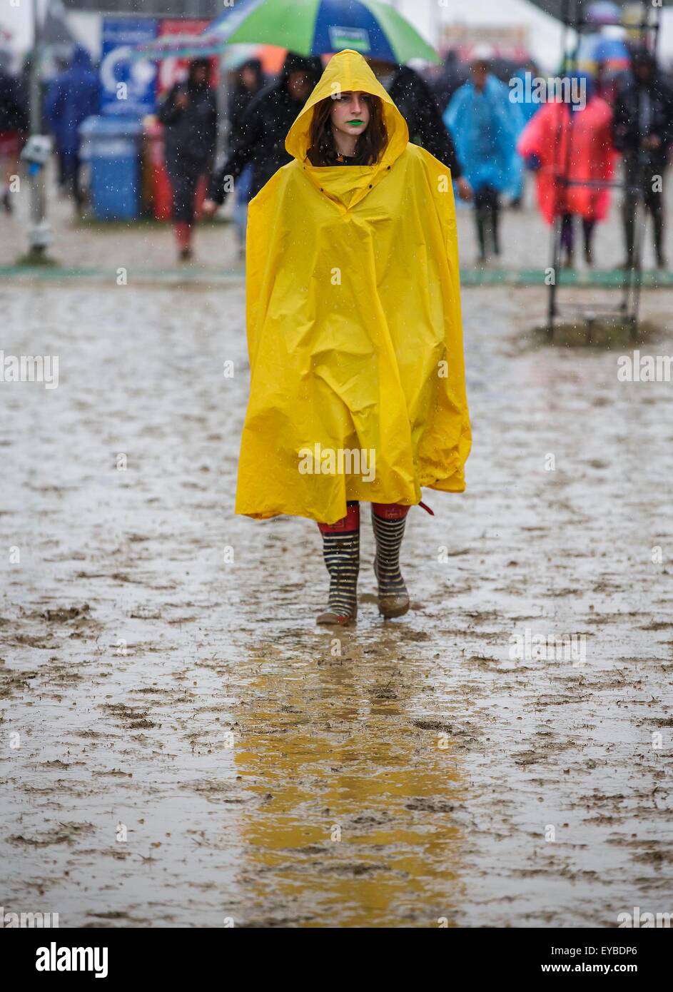 Malmesbury, Wiltshire, Regno Unito. 26 Luglio, 2015. Un festival goer passeggiate attraverso il fango e la pioggia a Womad Festival tenutosi a Charlton Park, nel Gloucestershire. Il 26 luglio 2015. Credito: Adam Gasson/Alamy Live News Foto Stock