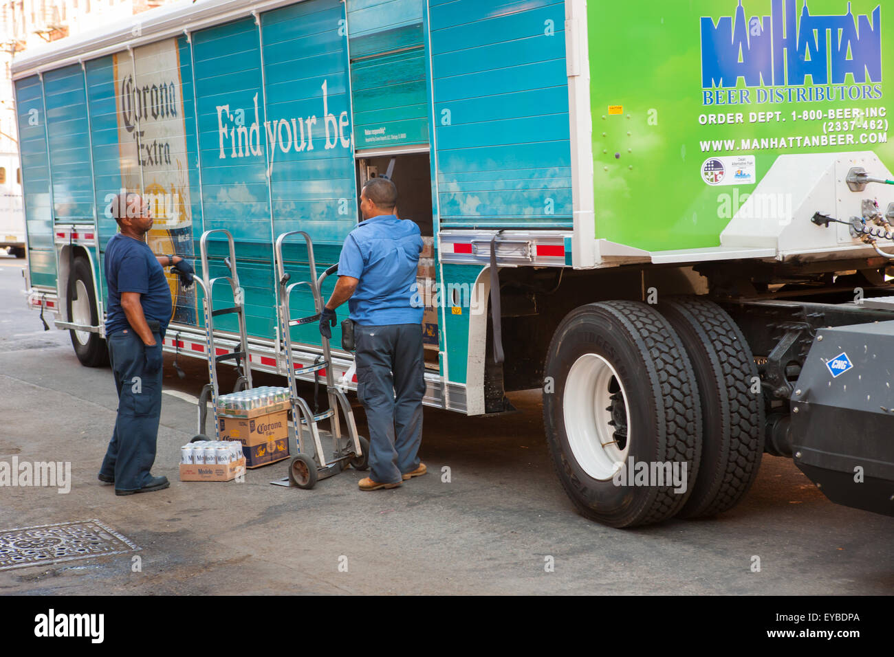 Due uomini scaricare la birra da un Manhattan distributori di birra bevanda carrello effettuare una consegna in Hamilton Heights in New York City. Foto Stock