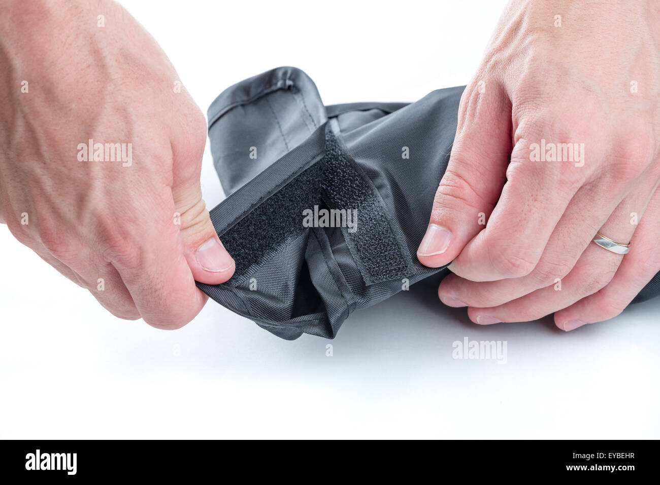 Un'immagine ravvicinata delle mani dell'uomo apertura di una scatola nera chiusa con un dispositivo di fissaggio in velcro su uno sfondo bianco. Foto Stock