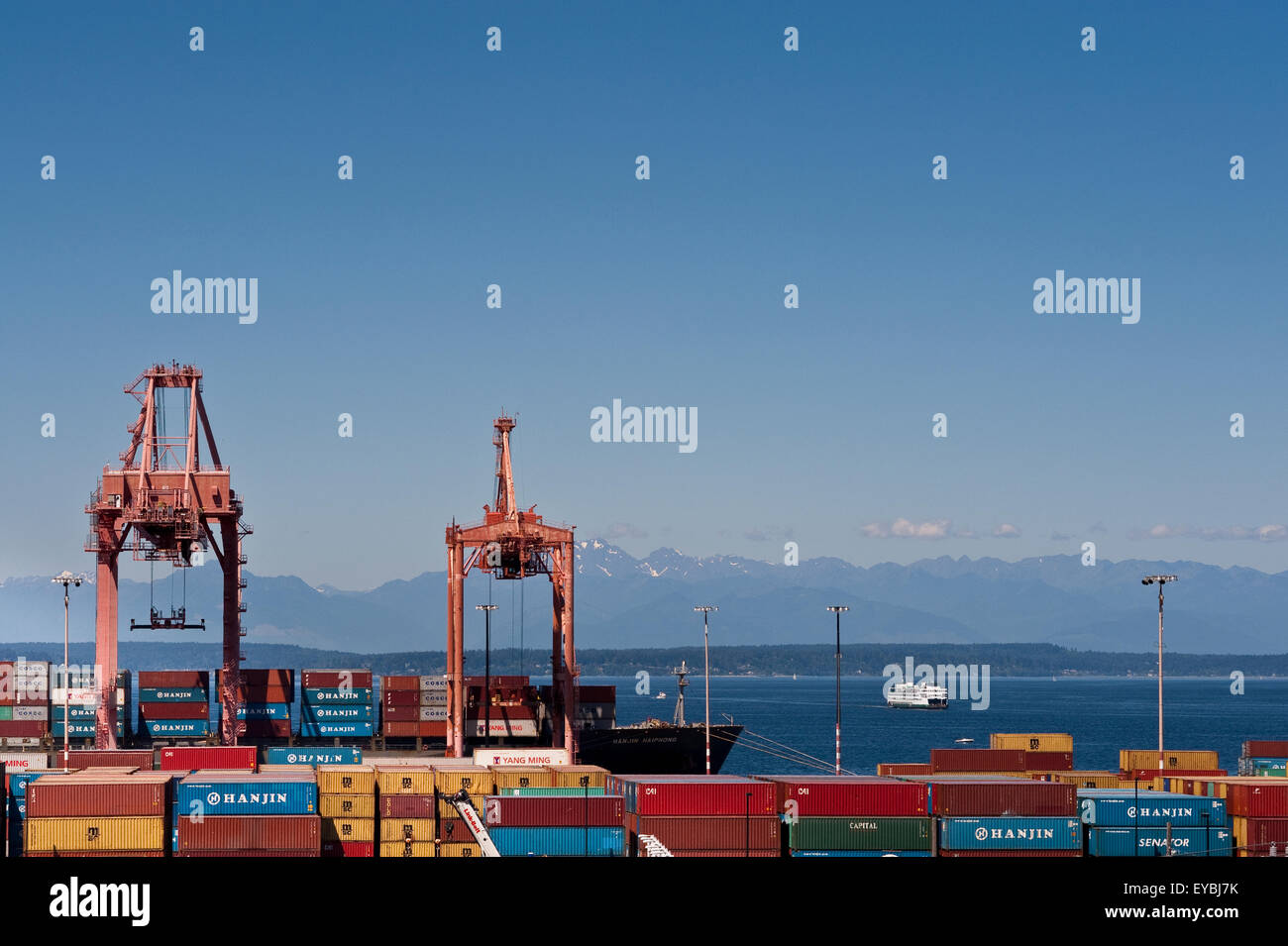 Porto di Seattle con grandi gru di scarico la nave da carico lungo Seattle Waterfront con montagne olimpiche Foto Stock